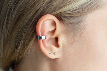 Cuff earring. Cropped shot of a young blonde woman wearing silver earring on the scapha. Jewelry,...