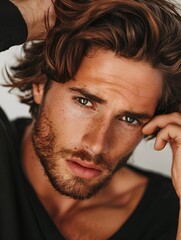 Fototapeta premium A portrait of a handsome male model touching his hair with his hands