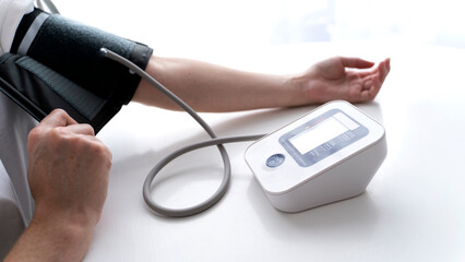 the girl measures blood pressure with a blood pressure monitor