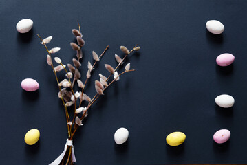 Easter multicolored pastel eggs and willow catkins on blue paper background. Empty copy space.