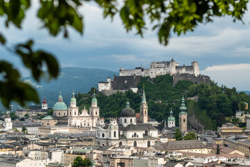An early summer cloudy day in the historic centre of Salzburg in Austria framed with green leaves...