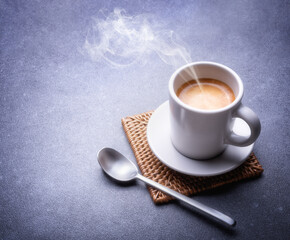Steaming espresso coffee on gray background, close-up, space for text.