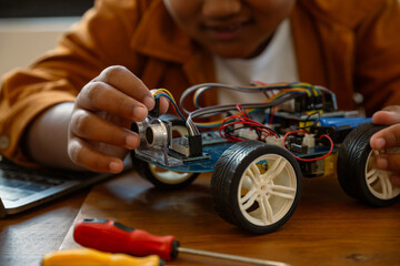 Little African boy doing robot  project in science classroom. technology of robotics programing and...