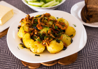 Baked potatoes with chanterelles, served with herbs on white plate