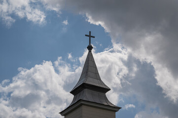 Fototapeta na wymiar cross on the bell tower or dome of an old church against a background of clouds in europe