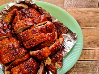 Close-up Roasted duck is on a green plate and a wooden background.