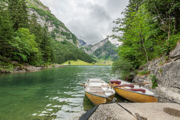 Beautiful summer view on lake Seealpsee in the Swiss alps, 2 rowing boats are lying in the water in...