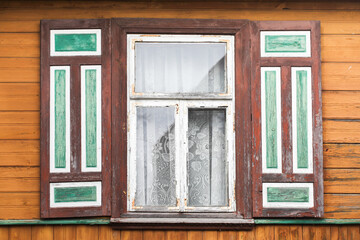 Fototapeta na wymiar Wooden rustic window in cottage house. Abandoned forsaken wooden home. Ancient architecture. Podlasie region in Poland vintage wall. Peeling paint decorative exterior shutter.