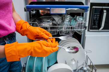 Young woman takes dishes out of the dishwasher machine