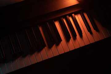 Keys of a keyboard instrument (piano, grand piano, synthesizer) with warm orange backlight....