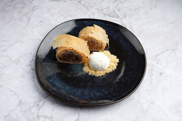 Sweet apple strudel with vanilla ice cream on a black plate
