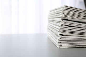 Stack of newspapers on grey table, space for text. Journalist's work - obrazy, fototapety, plakaty