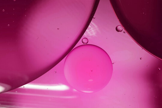 Magenta drops of oil or serum texture background. Oil drops on the water's surface. Macro photography