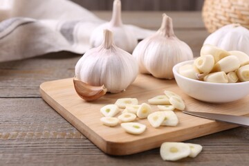 Aromatic cut garlic, cloves and bulbs on wooden table, closeup