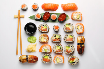 Set of delicious sushi rolls on white background, flat lay