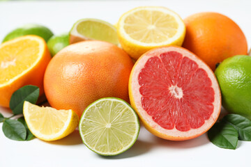 Different fresh citrus fruits and leaves on white table, closeup