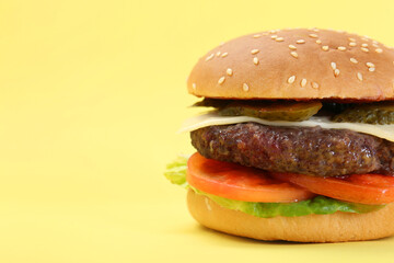 Burger with delicious patty on yellow background, closeup. Space for text