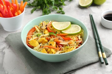 Stir-fry. Delicious cooked noodles with chicken and vegetables in bowl served on gray textured table