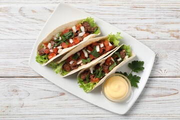 Delicious tacos with meat and vegetables served on wooden table, top view