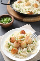 Delicious scallop pasta with green onion served on grey table