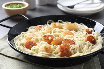 Delicious scallop pasta with green onion served on grey table, closeup