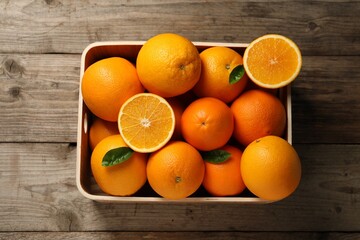 Many whole and cut ripe oranges on wooden table, top view
