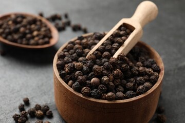 Aromatic spice. Pepper in bowl and scoop on black table, closeup
