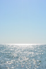 Beautiful border between the blue sky and the black sea with small waves and fine golden and bright...