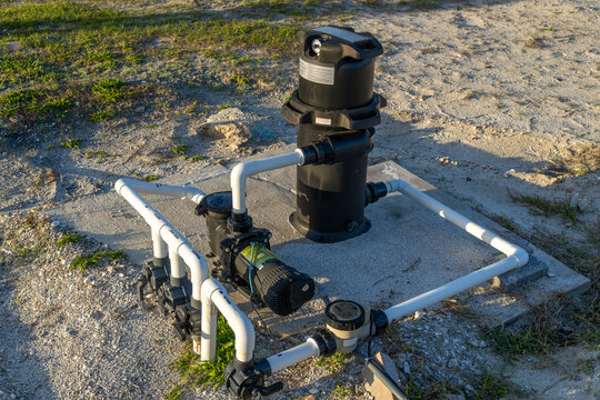 Pool equipment on a cement pad in sandy soil, filter, pump, valve, chlorinator