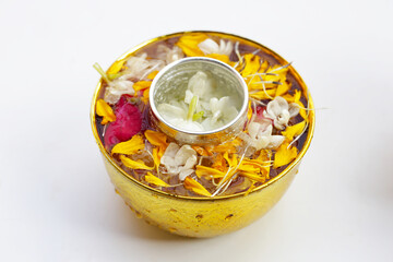 Water with jasmine flower, marigold petals and rose petals in golden bowl. Thai tradition, Songkran festival concept