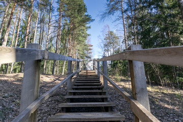 
A wooden staircase with a handrail on a small hill path