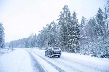 Car on the road in winter forest. Snowfall in Finland.