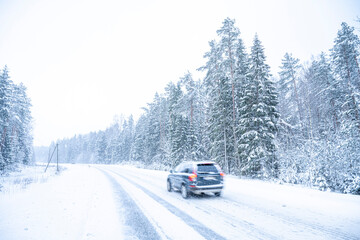 Car on the road in winter forest. Snowfall in Finland.