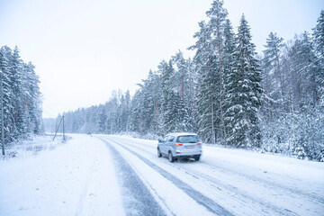 Car on the road in winter forest. Snowfall in Finland.