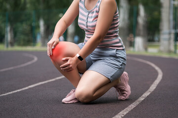 Diseases of the knee joint, bone fracture and inflammation, athletic woman on a running track after workout suffering from pain in leg and doing self-massage - 749944530