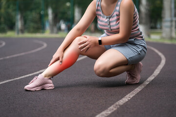 The woman's calf muscle cramped, massage of female leg on a sports ground after workout, health problems concept - 749944547