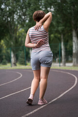 Back pain, athletic woman with backache on a running track after workout - 749944777