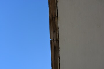 Dark blue sky with white clouds, the top of a tree, a white cement roof and a wooden beam.