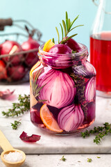 A jar of pickled red onions on a blue background.