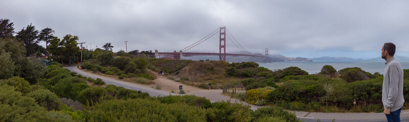 A man enjoying the view of the Golden Gate Bridge from the Battery East Vista overlook at Presidio of San Francisco in San Francisco, California, USA.