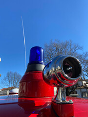 Vintage siren, antenna, and a blue rotating beacon on the roof of a red ambulance from the Santo...