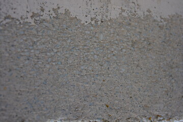 Reinforced concrete wall with cement mortar, small gray stones and white plaster
