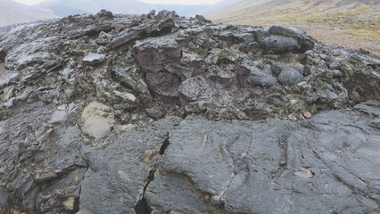View of cracked lava crust or ingenious rock and steam cooled down from the 2021 eruption of Fagradalsfjall volcano in Geldingadalir Valley on Reykjanes Peninsula in Iceland.