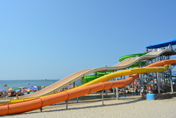 Water inflatable attraction of red, yellow and blue, a water furnace with a pool on the beach of...