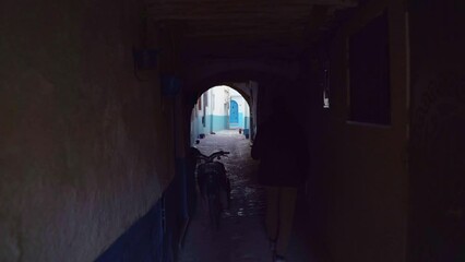 A man walks along a narrow street in the Old Medina. Shooting from the back.