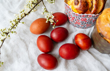 This festive Easter setting features red eggs, blossoms, and pastries on textured fabric.