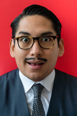 Eccentric Latin man wearing glasses looking surprised on the red background