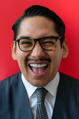 Eccentric Latin man wearing glasses smiling on the red background