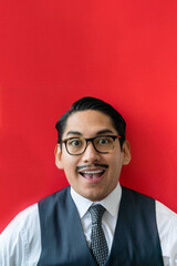 Eccentric Latin man wearing glasses smiling on the red background