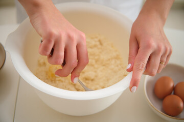 Obraz na płótnie Canvas Close up of woman's hands kneading dough in a bowl. Process of cooking pecan pie in home kitchen for American Thanksgiving Day.